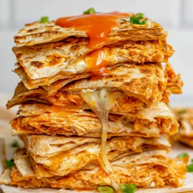 Buffalo chicken quesadillas stacked on a plate, perfect for game day snacks.