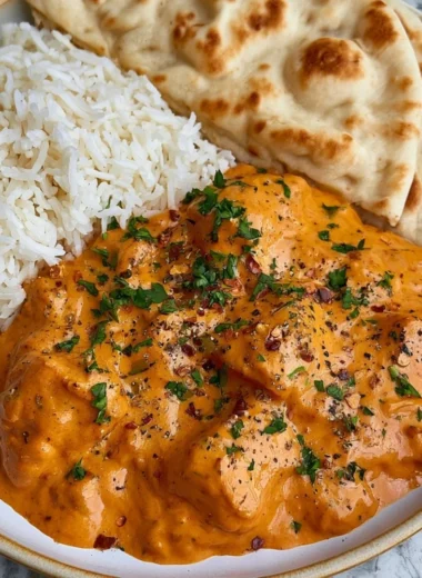 A delicious plate of homemade butter chicken served with rice and garnished with cilantro.