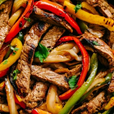 Delicious skillet steak fajitas with peppers and onions served on a plate.