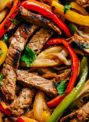 Delicious skillet steak fajitas with peppers and onions served on a plate.