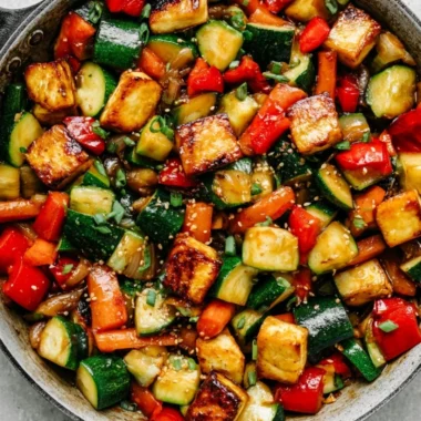 Delicious vegan zucchini stir fry with tofu and colorful vegetables in a bowl.