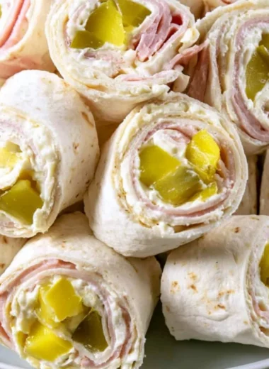 Savory pickle dip pinwheels served on a plate, garnished with herbs.